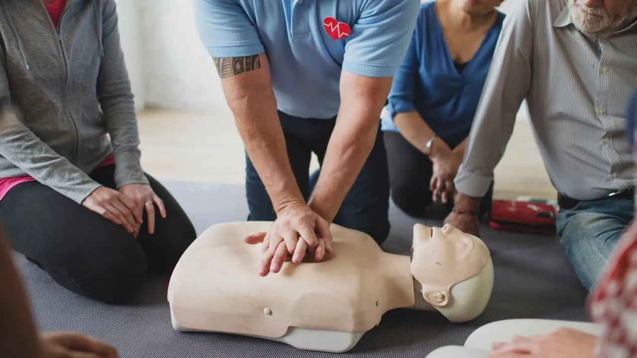 CPR instructor demonstrating proper hand placement and chest compressions on an adult training manikin.